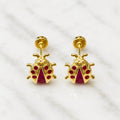 14K yellow gold ladybug screw back stud earrings with red CZ body accents on marble surface