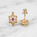 14K yellow gold turtle stud earrings with red CZ center and white CZ cluster shown front and back view on marble surface