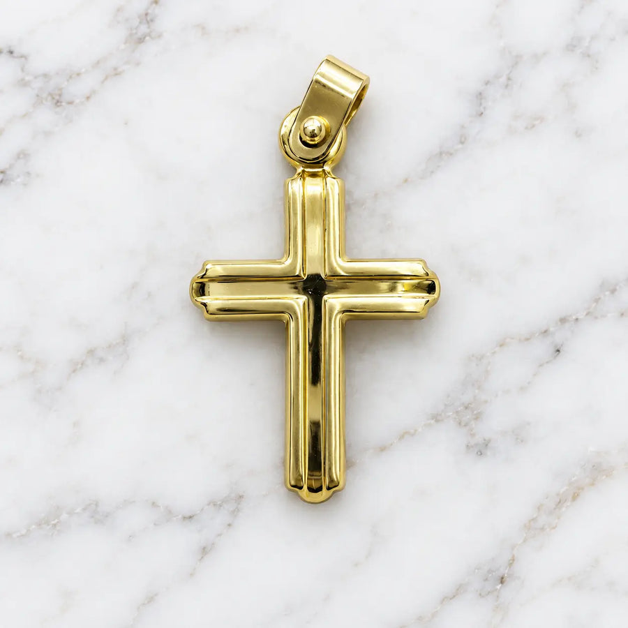 14K yellow gold polished grooved cross pendant with budded tips and ball-accent bail on white marble surface