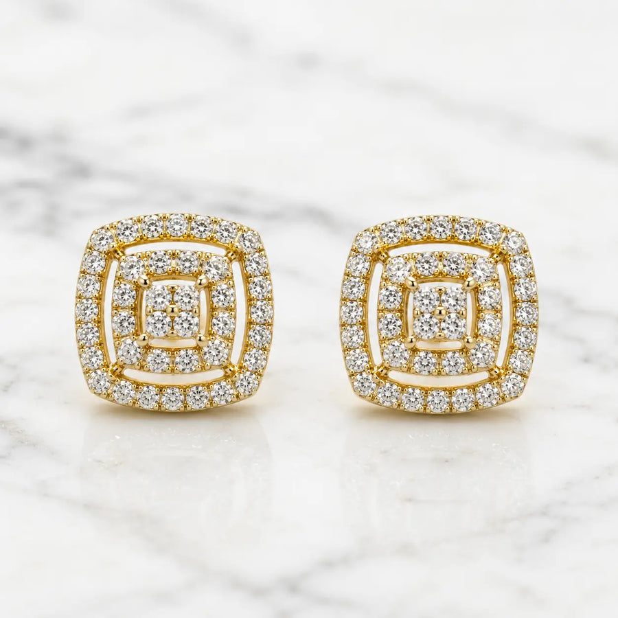 Gold tone over sterling silver 1 CTW moissanite cushion cluster stud earrings on white marble surface