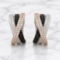 Sterling silver crisscross CZ clip earrings with black, white, and rose-tone pavé rows on marble surface