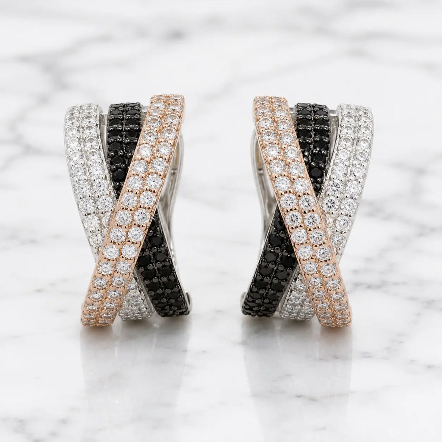 Sterling silver crisscross CZ clip earrings with black, white, and rose-tone pavé rows on marble surface