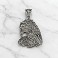 Back view of sterling silver eagle head pendant showing openwork detail and stone settings on marble surface