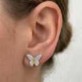 Sterling silver butterfly pavé CZ stud earrings with yellow CZ body worn on ear showing scale and fit