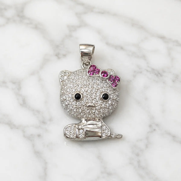 Sterling silver cat pendant with clear CZ pavé and pink bow on white marble surface