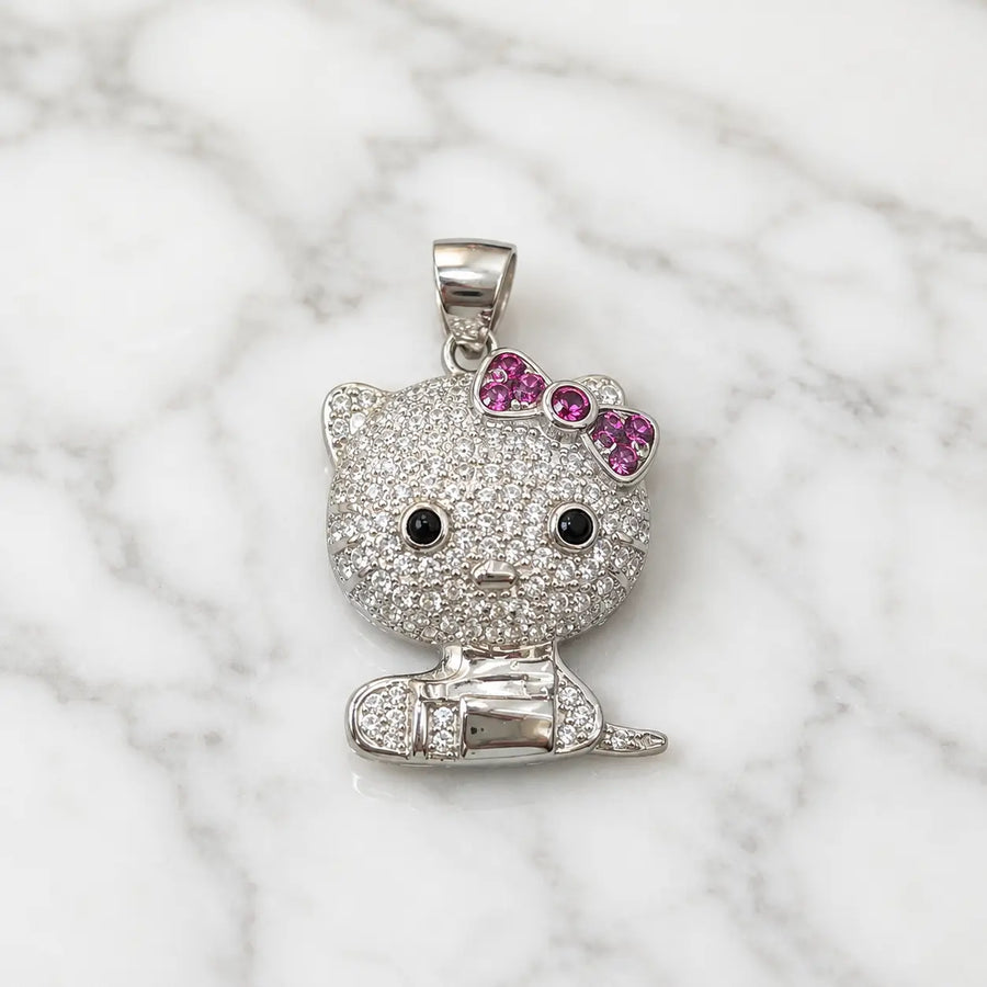 Sterling silver cat pendant with clear CZ pavé and pink bow on white marble surface