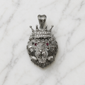 Sterling silver crowned lion pendant with white CZ crown accents and red CZ eyes on marble surface
