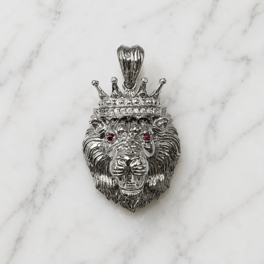Sterling silver crowned lion pendant with white CZ crown accents and red CZ eyes on marble surface