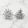 Sterling silver cubic zirconia snowflake starburst stud earrings showing front and friction back closure on marble surface
