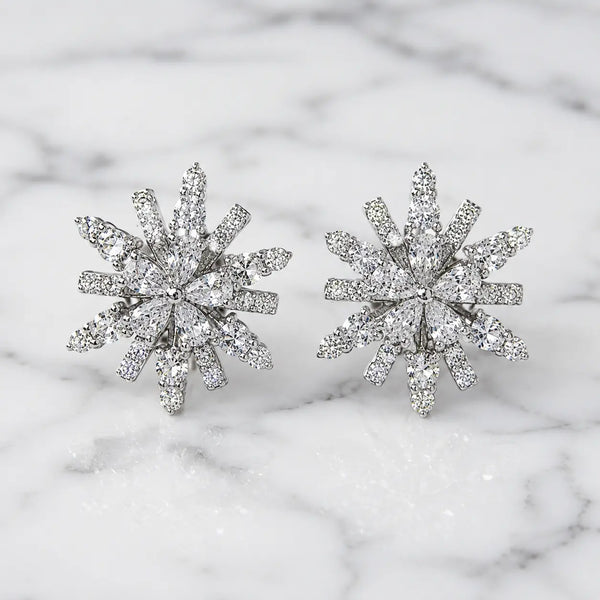 Sterling silver cubic zirconia snowflake starburst stud earrings with brilliant multi-cut stones on marble surface