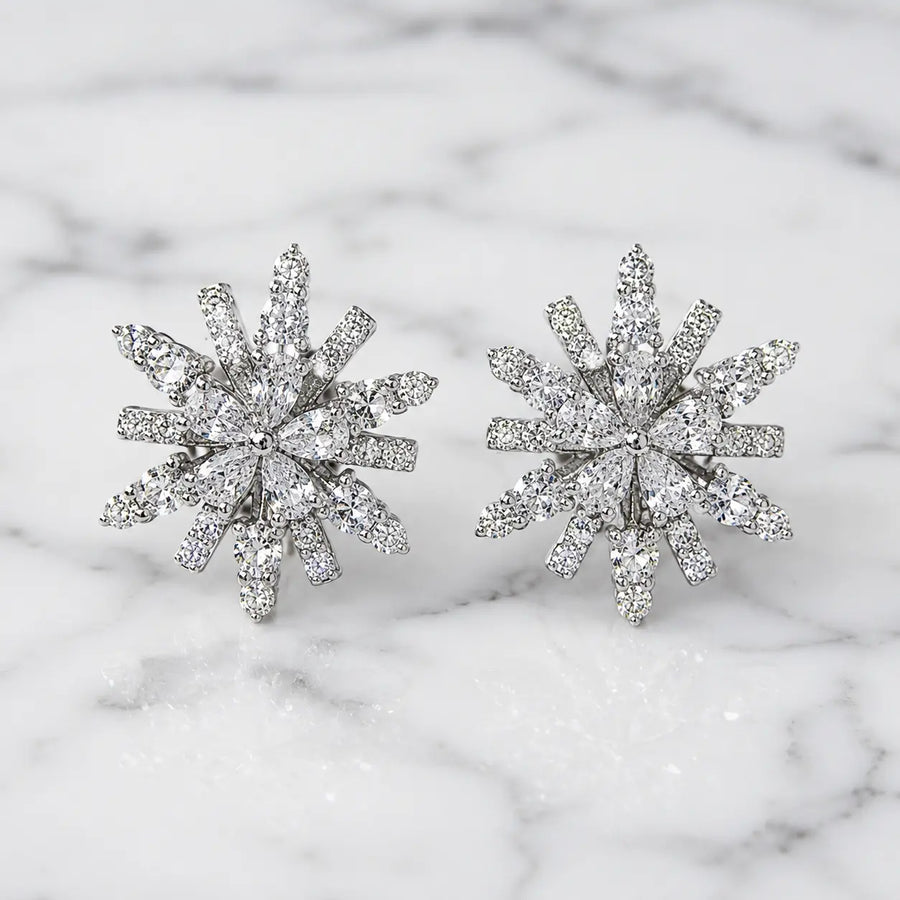 Sterling silver cubic zirconia snowflake starburst stud earrings with brilliant multi-cut stones on marble surface