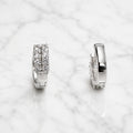Sterling silver double-row CZ huggie earrings front and side view on marble surface
