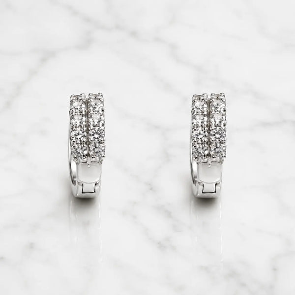 Sterling silver double row CZ huggie earrings with hinged hoop design on marble surface
