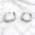 Sterling silver double-row CZ huggie earrings open showing hinged snap closure on marble surface