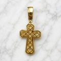Back view of gold tone sterling silver crucifix pendant with openwork design shown on marble surface