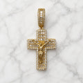 Gold tone sterling silver crucifix pendant with baguette and round CZ stones, front view on marble surface