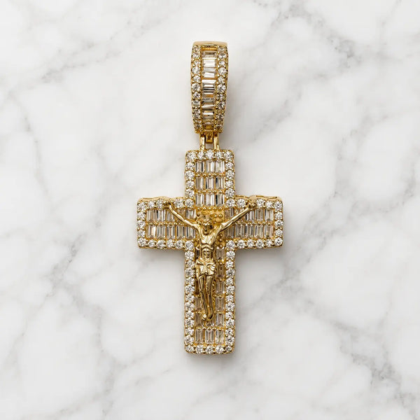 Gold tone sterling silver crucifix pendant with baguette and round CZ stones, front view on marble surface