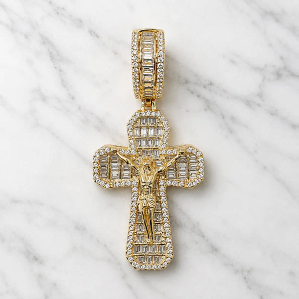 Gold tone sterling silver crucifix pendant with baguette and round CZ stones shown from the front on marble surface