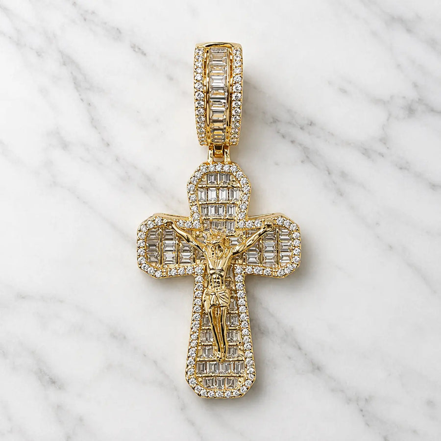 Gold tone sterling silver crucifix pendant with baguette and round CZ stones shown from the front on marble surface