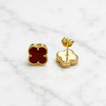Sterling silver gold-tone red clover stud earrings with push-back post detail on marble surface