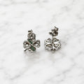 Sterling silver green CZ clover stud earrings with push-back post and back detail on marble surface