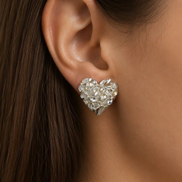 Sterling silver large diamond-cut heart stud earring worn on ear showing bold heart size