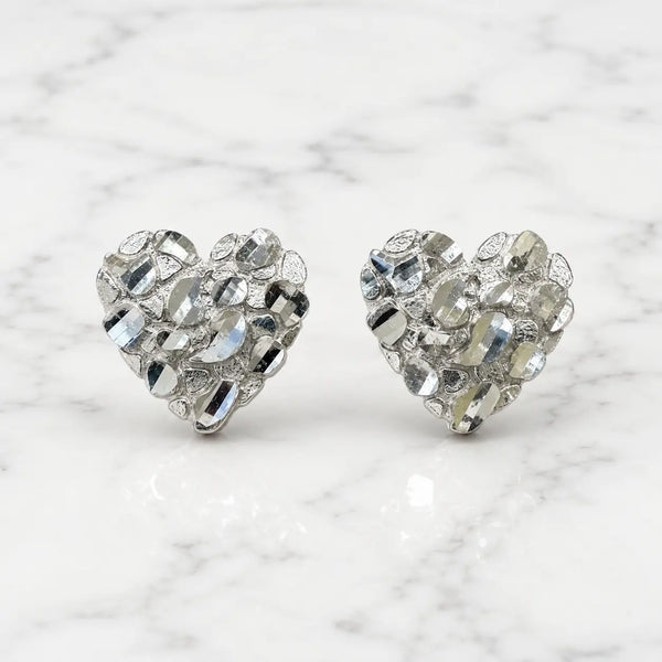 Sterling silver medium diamond-cut heart stud earrings front view pair on marble surface