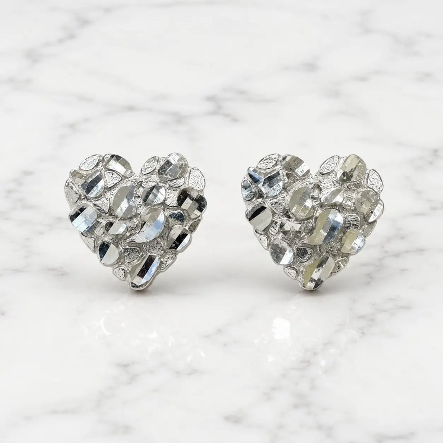 Sterling silver medium diamond-cut heart stud earrings front view pair on marble surface