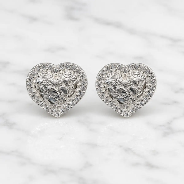 Sterling silver textured heart CZ stud earrings with pavé-style border on marble surface