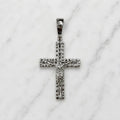 Sterling silver ornate crucifix pendant front view with raised Jesus figure and decorative border on white marble surface
