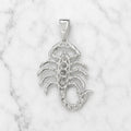 Back view of sterling silver scorpion pendant showing open stone settings and polished detail on marble surface