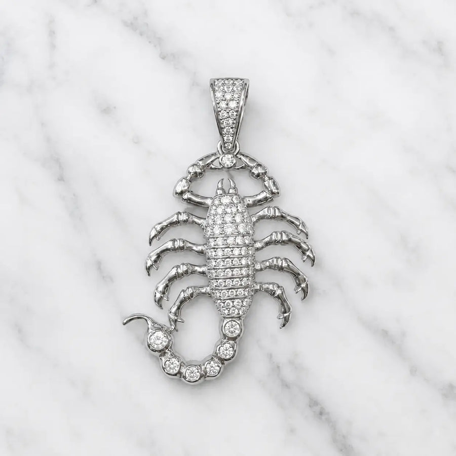 Sterling silver scorpion pendant with pavé clear CZ body, tail and bail shown front-facing on marble surface