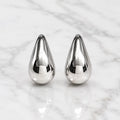 Sterling silver polished teardrop stud earrings front view with mirror-finish dome on marble surface
