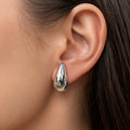 Sterling silver polished teardrop stud earring worn on ear showing 20.2mm drop size and shine