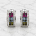 Sterling silver rainbow CZ huggie earrings front view on marble with heart-shaped clear CZ top accents
