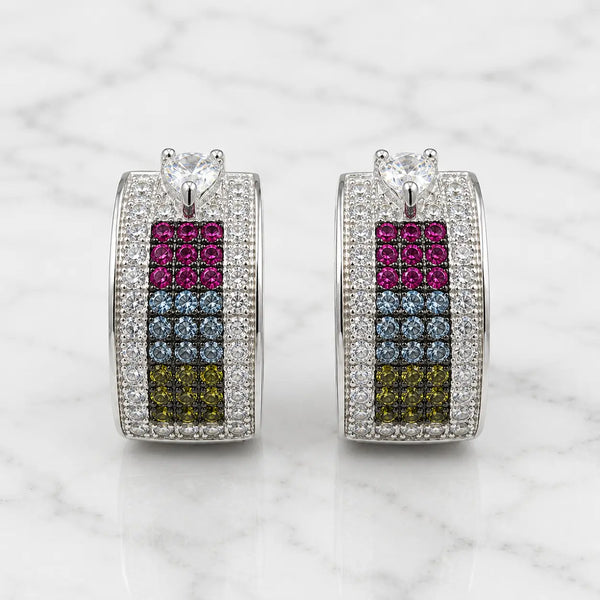 Sterling silver rainbow CZ huggie earrings front view on marble with heart-shaped clear CZ top accents