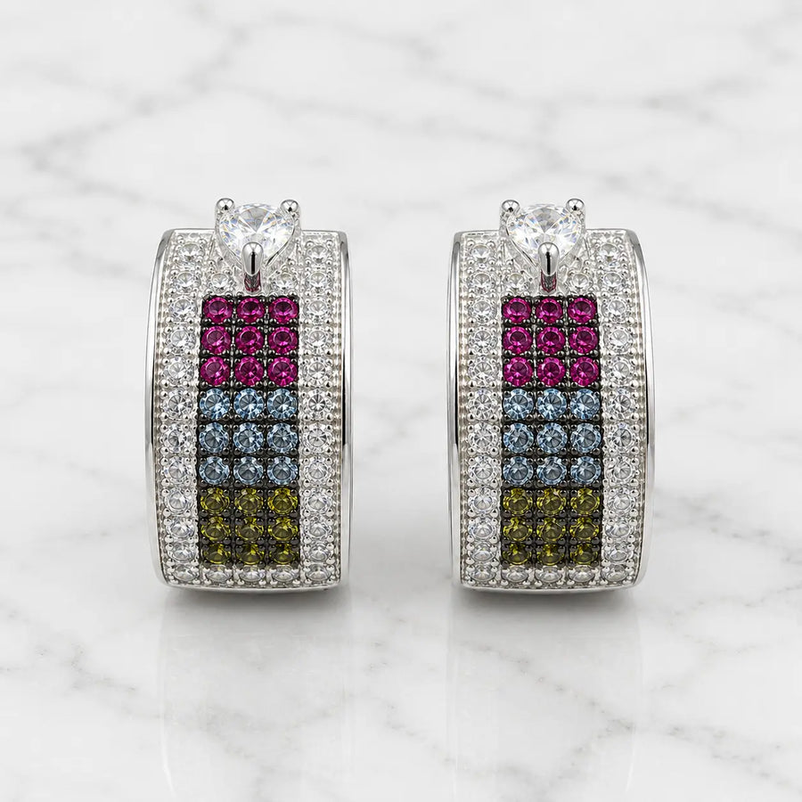Sterling silver rainbow CZ huggie earrings front view on marble with heart-shaped clear CZ top accents