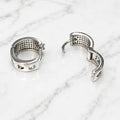 Sterling silver rainbow CZ huggie earrings open on marble showing hinged snap closure and polished finish