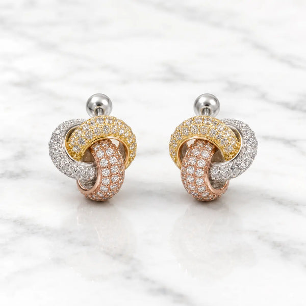 Sterling silver tri-color CZ knot stud earrings front pair with pavé-style sparkle on marble surface