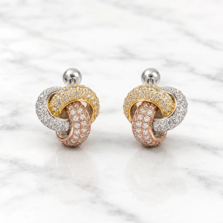 Sterling silver tri-color CZ knot stud earrings front pair with pavé-style sparkle on marble surface