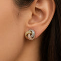 Sterling silver tri-color CZ knot stud earring worn on ear showing compact knot design and sparkle