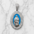 Front view of sterling silver Virgin Mary oval pendant with white CZ border and blue center on marble surface