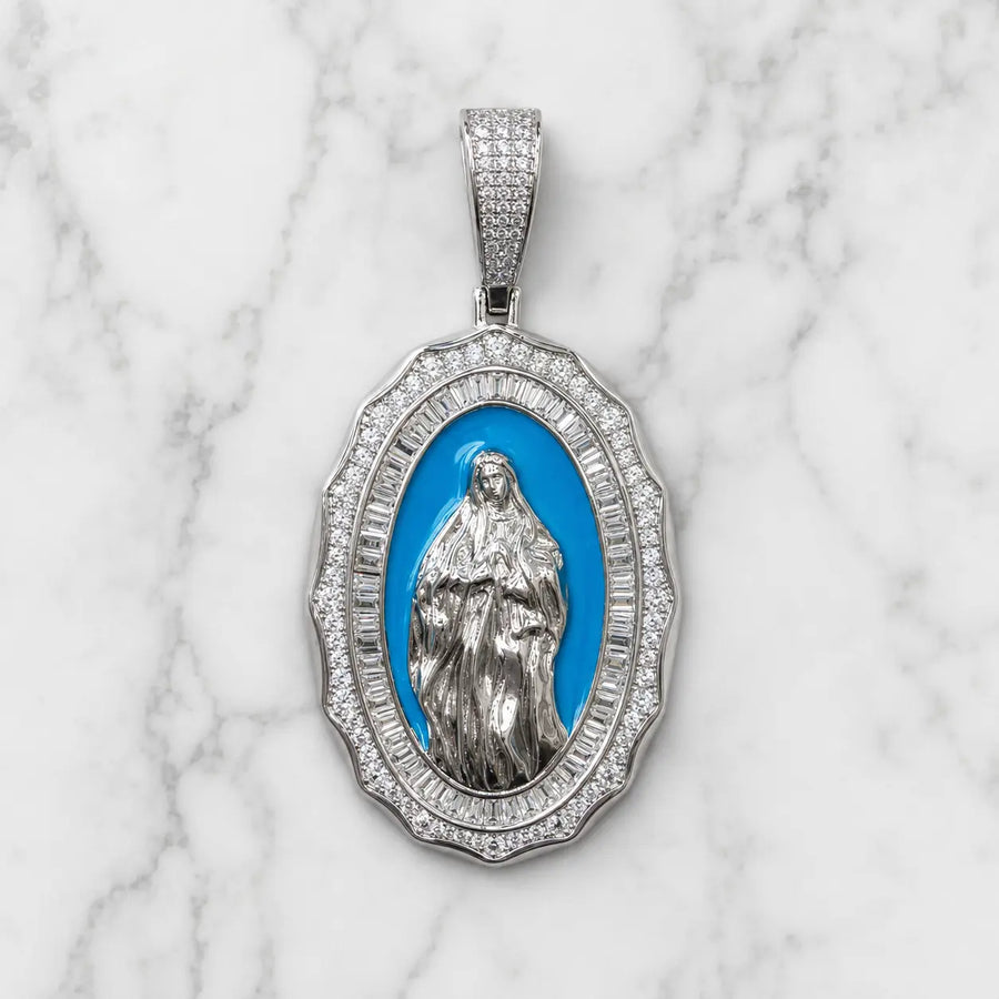 Front view of sterling silver Virgin Mary oval pendant with white CZ border and blue center on marble surface