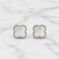 Sterling silver white clover stud earrings with polished beaded border on marble surface