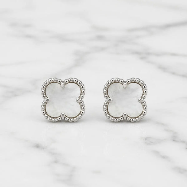 Sterling silver white clover stud earrings with polished beaded border on marble surface