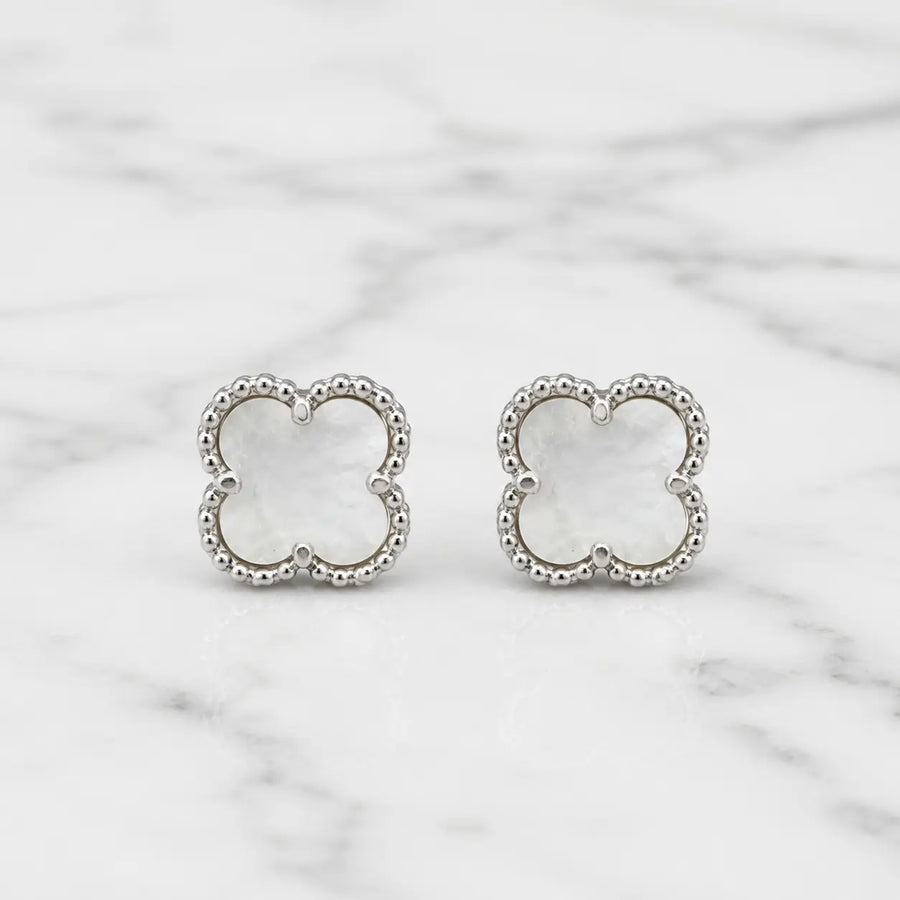 Sterling silver white clover stud earrings with polished beaded border on marble surface
