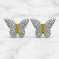 Sterling silver butterfly stud earrings with pavé clear CZ wings and yellow CZ body stones on marble surface