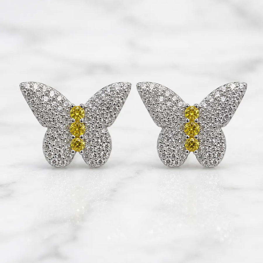 Sterling silver butterfly stud earrings with pavé clear CZ wings and yellow CZ body stones on marble surface
