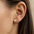 Yellow gold tone sterling silver moissanite halo stud earring worn on the ear showing its petite 7.9mm size